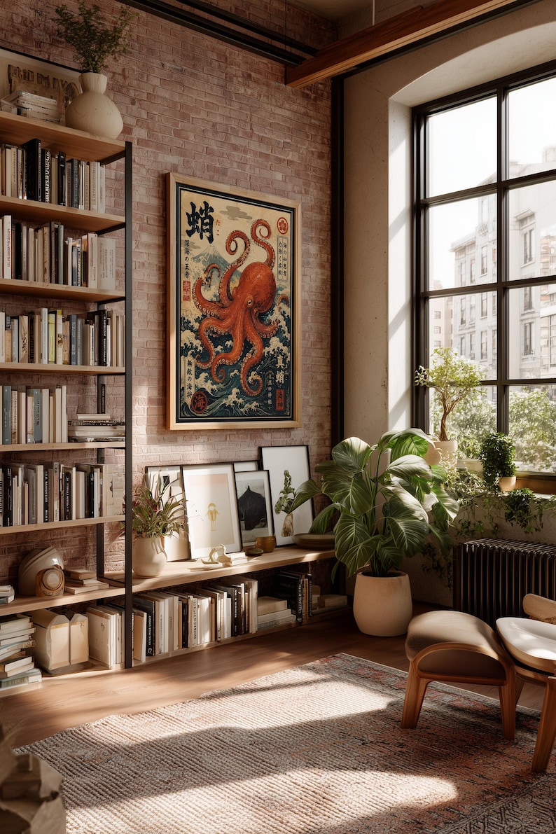 May include: A framed wall art print featuring a large orange octopus over stylized blue ocean waves with Mount Fuji in the background and Japanese text characters, displayed on a brick wall in a room with bookshelves and a large window.