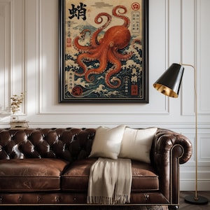May include: A framed wall art print featuring a large orange octopus centered over stylized blue ocean waves. The artwork includes Japanese kanji characters, a mountain silhouette in the background, and red circular stamps, all set within a black frame.