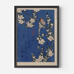 May include: A vintage Japanese woodblock print depicting two birds perched on a branch of white blossoms against a blue background. The print includes Japanese text.