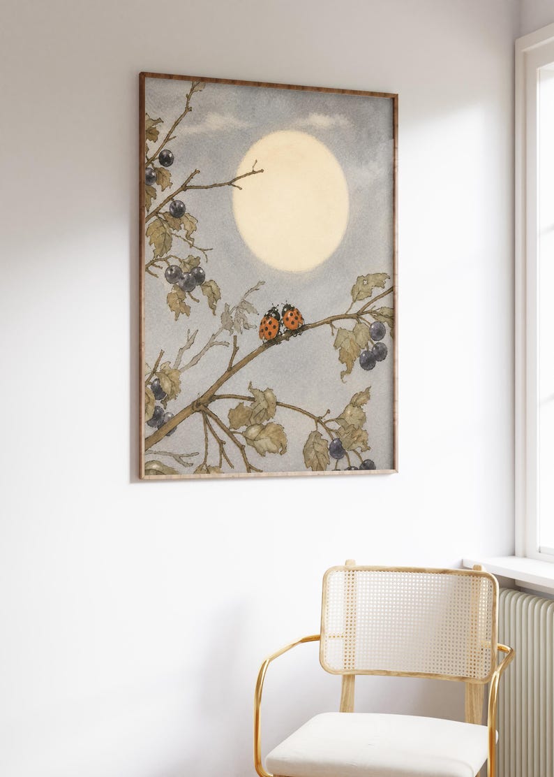 May include: A framed art print with a watercolour illustration of a moonlit scene. Two ladybirds sit on a branch with berries, set against a soft blue sky and a large, glowing moon. The artwork has a vintage aesthetic.