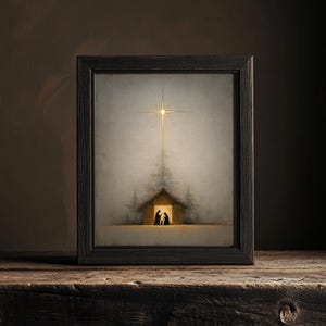 May include: Framed art print depicting a nativity scene. The artwork features a star shining above a small building with silhouetted figures inside. The frame is dark, and the overall aesthetic is serene and evocative.