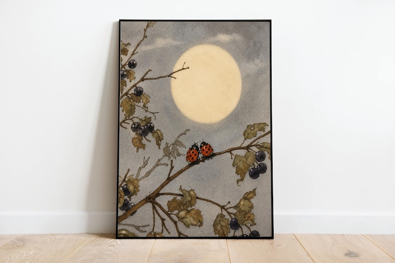 May include: Framed art print showing a watercolour illustration of a full moon in a cloudy sky. Two red ladybirds with black spots sit on a branch with leaves and dark berries. The artwork is in a black frame.