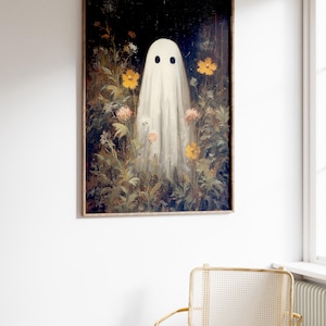 K&ouml;nnte beinhalten: Gerahmter Kunstdruck mit einem wei&szlig;en Geist mit zwei schwarzen Augen, der inmitten eines Feldes aus gelben und rosa Blumen steht. Das Kunstwerk hat eine Vintage-&Auml;sthetik mit dunklem Hintergrund und Holzrahmen. Thema: Halloween.