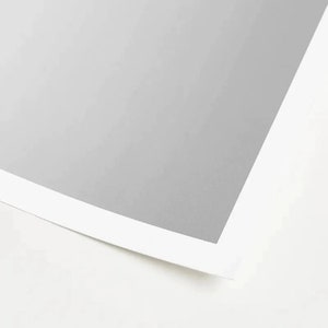 May include: A close-up of a white sheet of paper with a gray border. The paper is slightly curled at the edges.
