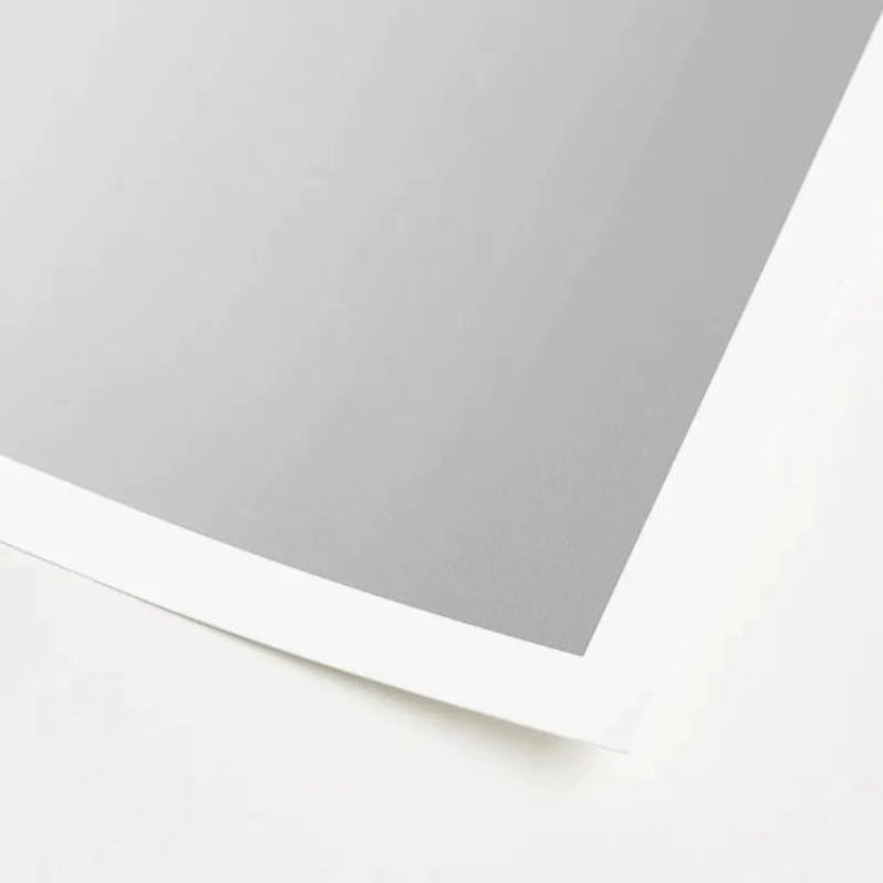 May include: A close-up of a white sheet of paper with a gray border. The paper is slightly curled at the edges.