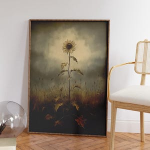 Peut inclure: Une impression encadr&eacute;e d'un seul tournesol se dressant dans un champ d'herbes et de feuilles s&eacute;ch&eacute;es. Le tournesol est jaune avec un centre fonc&eacute; et est &eacute;clair&eacute; par une lumi&egrave;re vive. L'arri&egrave;re-plan est d'un vert et d'un brun ternes.