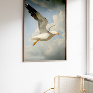Puede incluir: Una pintura enmarcada de una gaviota blanca con puntas de alas negras volando en un cielo nublado. La gaviota est&aacute; enfocada y el cielo est&aacute; desenfocado en el fondo.
