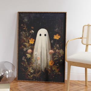 K&ouml;nnte beinhalten: Gerahmter Kunstdruck mit einem wei&szlig;en Geistermotiv mit schwarzen Augen, umgeben von orangefarbenen und rosa Blumen. Das Kunstwerk hat einen dunklen Hintergrund und einen Vintage-Stil, passend f&uuml;r Halloween.