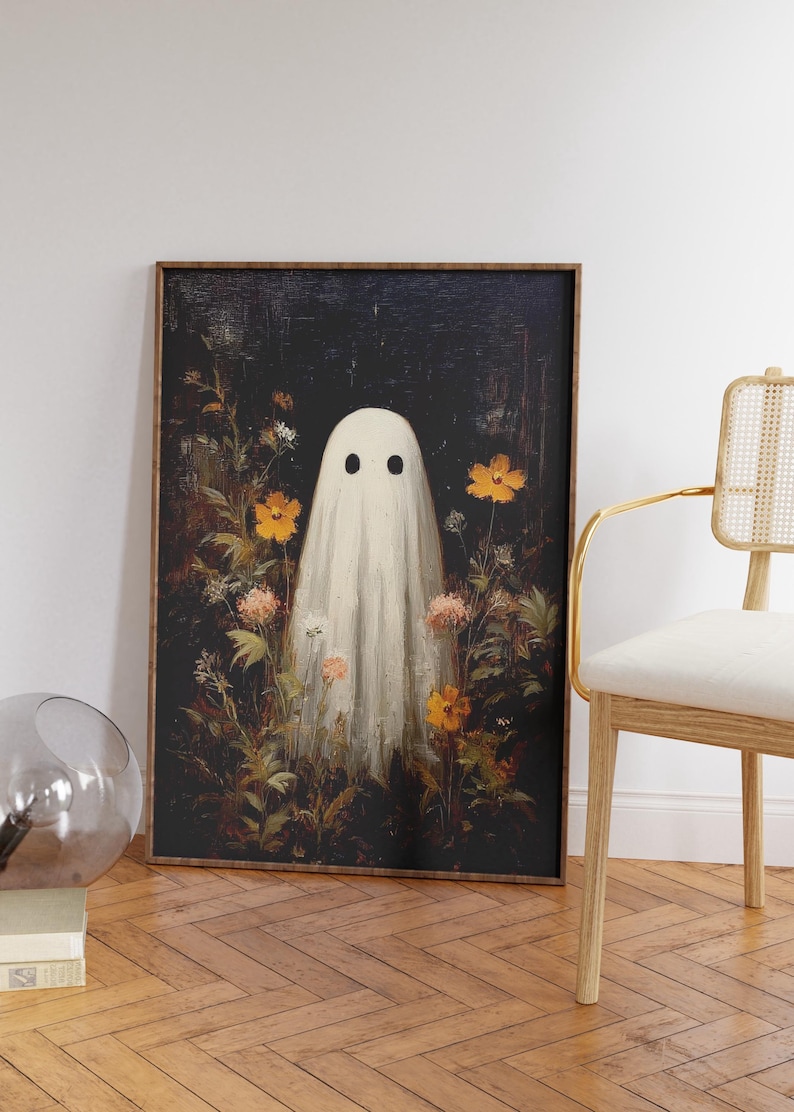 K&ouml;nnte beinhalten: Gerahmter Kunstdruck mit einem wei&szlig;en Geistermotiv mit schwarzen Augen, umgeben von orangefarbenen und rosa Blumen. Das Kunstwerk hat einen dunklen Hintergrund und einen Vintage-Stil, passend f&uuml;r Halloween.