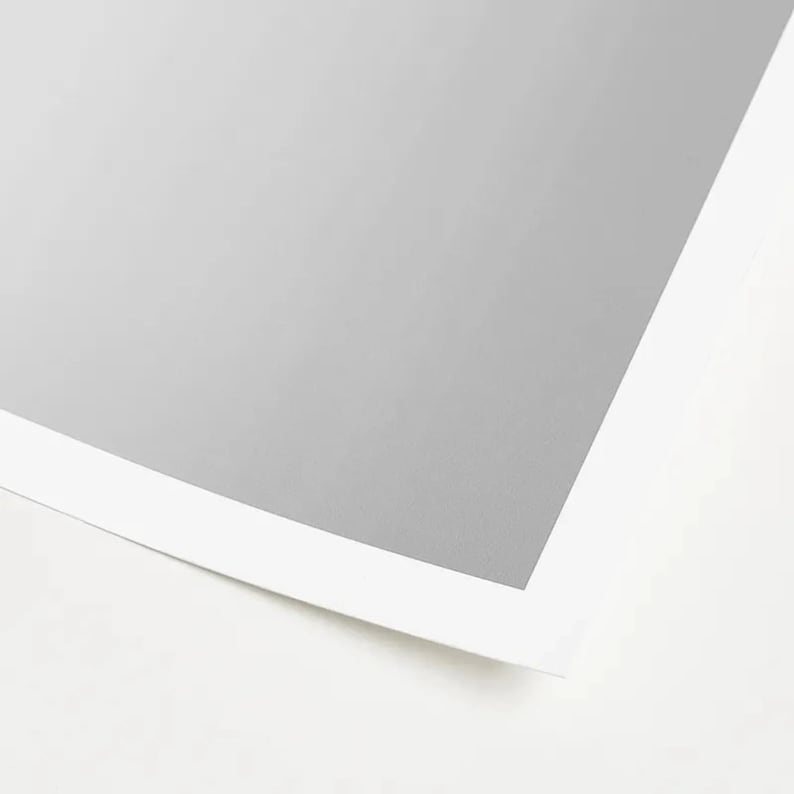 May include: A close-up of a white sheet of paper with a gray border. The paper is slightly curled at the bottom.
