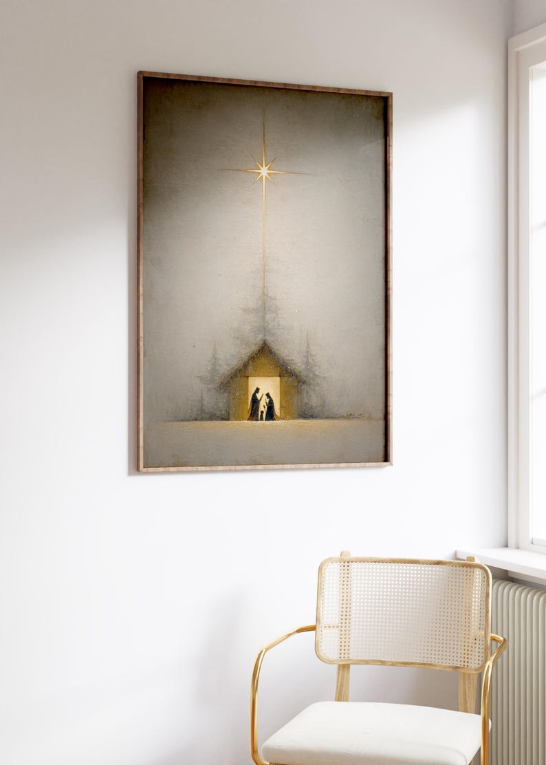 May include: Framed art print depicting a Nativity scene. The artwork features a golden star shining above a simple building with figures inside. The color palette is muted with soft grays and golds, creating a serene atmosphere. The frame is a warm, natural wood tone.