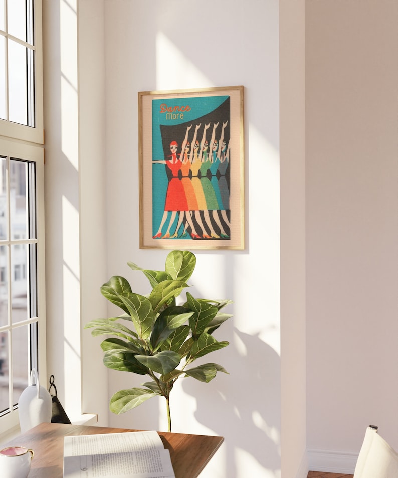 May include: A framed poster with a retro design featuring a line of women in colorful dresses dancing. The poster has a blue background with a rainbow gradient and the text "Dance More".