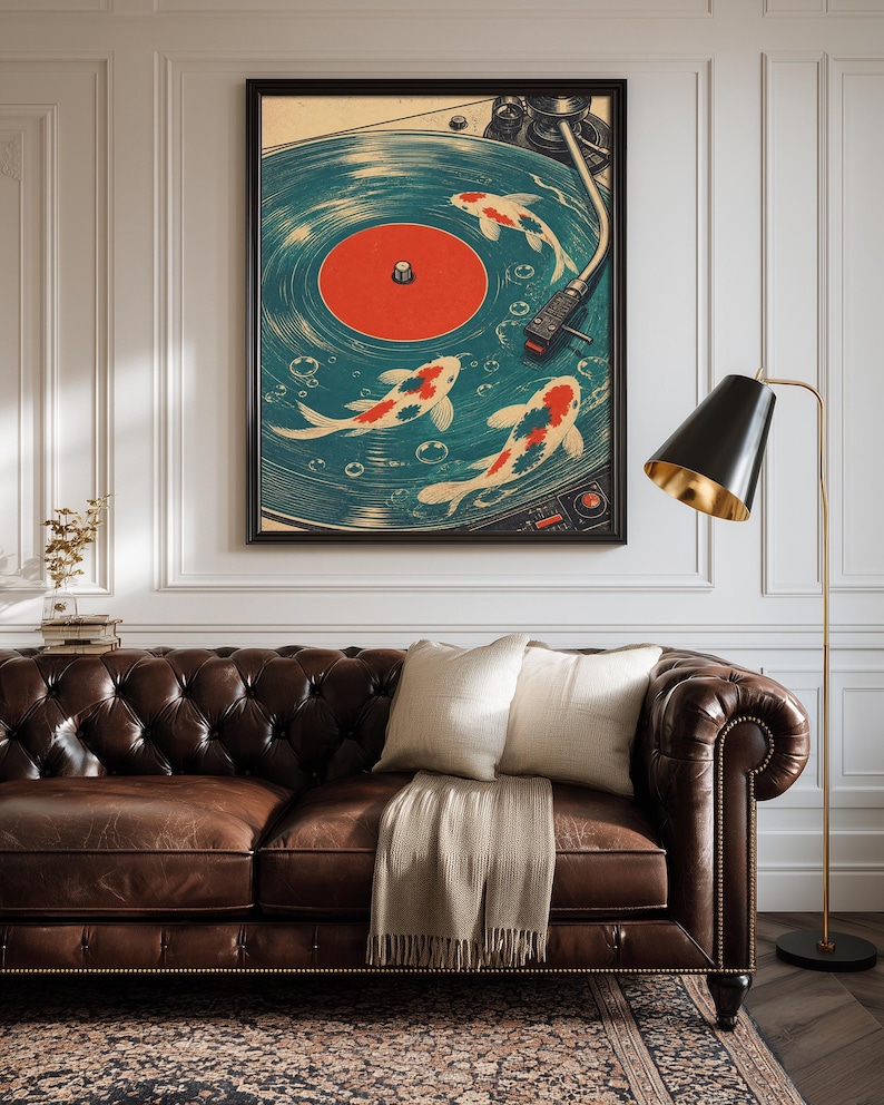 Puede incluir: Una impresi&oacute;n art&iacute;stica enmarcada que presenta un dise&ntilde;o de tocadiscos vintage con peces koi nadando en el disco. La obra de arte tiene una combinaci&oacute;n de colores turquesa y naranja, con un marco negro. La impresi&oacute;n se muestra sobre un sof&aacute; de cuero marr&oacute;n.