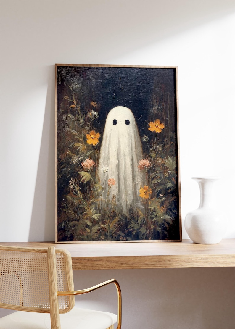 K&ouml;nnte beinhalten: Ein gerahmter Kunstdruck mit einem wei&szlig;en Geist mit schwarzen Augen in einem Blumenfeld. Das Kunstwerk hat eine Vintage-&Auml;sthetik mit dunklem Hintergrund und Holzrahmen. Die Blumen sind orange und wei&szlig;.