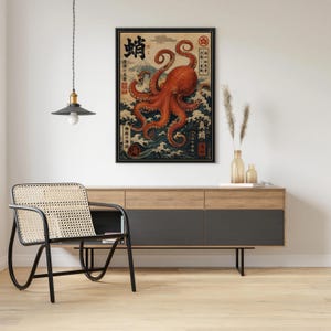 May include: A framed wall art print featuring a large orange octopus centered over stylized blue ocean waves and a mountain in the background. The artwork includes black Japanese kanji characters and red circular stamps arranged vertically and horizontally.
