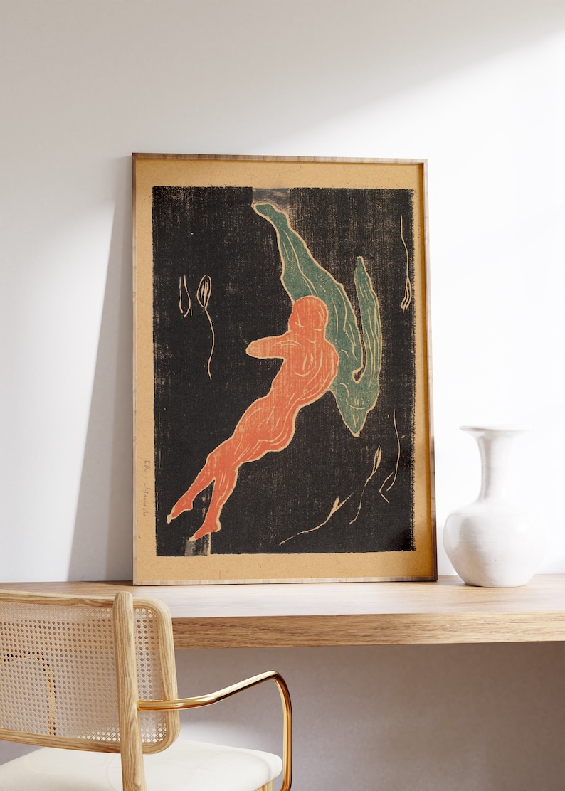 May include: A framed print of a black and white abstract art piece with a red and green figure in the center. The print is framed in a light wood frame.