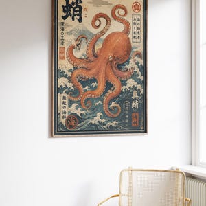 May include: A rectangular framed wall art print featuring a large orange octopus centered over dark blue stylized ocean waves. In the background, a mountain peak is visible. The print includes black Japanese kanji text and red circular stamps.