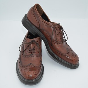 May include: A pair of brown leather brogue shoes with lace-up closures. The shoes have a wingtip design and a perforated pattern.