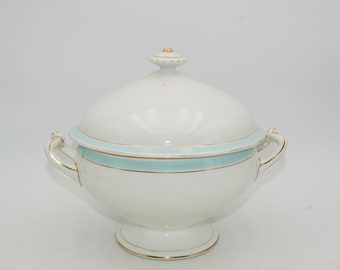 May include: White porcelain soup tureen with a light blue band and gold trim. The tureen has two handles and a lid with a knob.