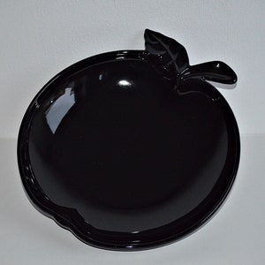 Könnte beinhalten: Eine schwarze, apfelförmige Servierplatte aus Keramik mit einem Blattdetail.