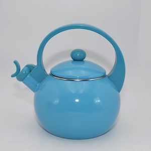 Könnte beinhalten: Ein hellblauer Emaille-Wasserkocher mit einem gebogenen Griff und einem Pfeifenauslauf. Der Wasserkocher hat eine glänzende Oberfläche und einen Edelstahlrand um den Deckel.