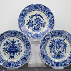 Könnte beinhalten: Drei blau-weiße Delft-Platten mit Blumendesigns. Die Teller haben einen weißen Hintergrund mit blauen Blumenmustern und blauen Rändern.
