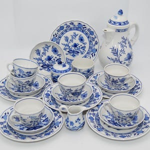 Puede incluir: Un juego de té de porcelana azul y blanco con un patrón floral. El juego incluye una tetera, una jarra de crema, un azucarero, tazas y platillos.