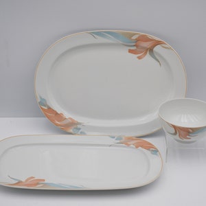 Könnte beinhalten: Ein Set aus drei weißen Keramik-Servierplatten mit einem floralen Design in Orange- und Blautönen. Die Platten haben einen goldenen Rand und sind oval.