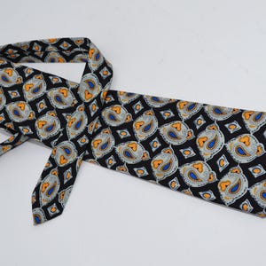 Könnte beinhalten: Eine schwarze Seidenkrawatte mit einem Paisley-Muster in Orange-, Blau- und Weißtönen.