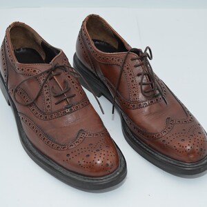 May include: A pair of brown leather brogue shoes with lace-up closures. The shoes have a wingtip design and a perforated pattern.