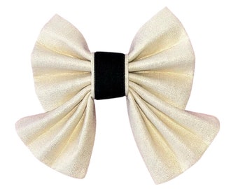 May include: A large, ivory-colored fabric bow with a black velvet center.