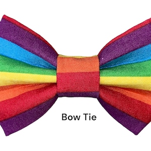 May include: A rainbow striped bow tie. The bow tie is made of fabric and has a purple, blue, green, yellow, orange, and red stripe pattern.