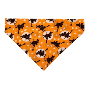 May include: Orange fabric dog bandana with a repeating pattern of black silhouettes of witches flying on broomsticks in front of a full moon with white stars.