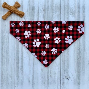 May include: Red and black plaid dog bandana with white paw prints.