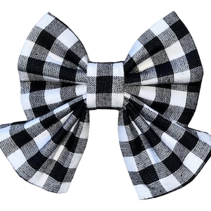 May include: A black and white checkered bow. The bow is made of fabric and has a large, rounded shape.