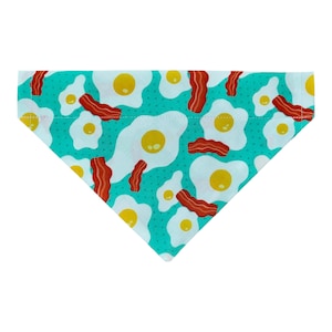May include: A turquoise blue dog bandana with a pattern of white eggs and red bacon.