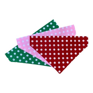 May include: Three dog bandanas in a stack. The top bandana is red with white polka dots, the middle bandana is pink with white polka dots, and the bottom bandana is green with white polka dots.