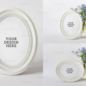 Peut inclure: Deux cadres photo ovales blancs sur fond blanc. Les cadres ont une bordure décorative et le texte "YOUR DESIGN HERE" est imprimé au centre de chaque cadre. Un bouquet de fleurs bleues myosotis est dans un vase en verre transparent à côté de chaque cadre.
