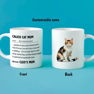 May include: White ceramic mug featuring a calico cat illustration and text. The front of the mug says "CALICO CAT MUM" with a definition. The mug has a curved handle and is set against a blue background. The text says "Customisable name".