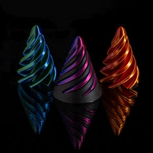 May include: Three decorative, spiral-shaped ornaments in blue, purple, and orange. The ornaments are made of metal and have a shiny finish.
