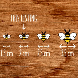 May include: Four bee illustrations in different sizes on a wood background. The bees are yellow and black with white wings. The sizes are 1.5 cm, 2 cm, 2.5 cm, and 3.5 cm.