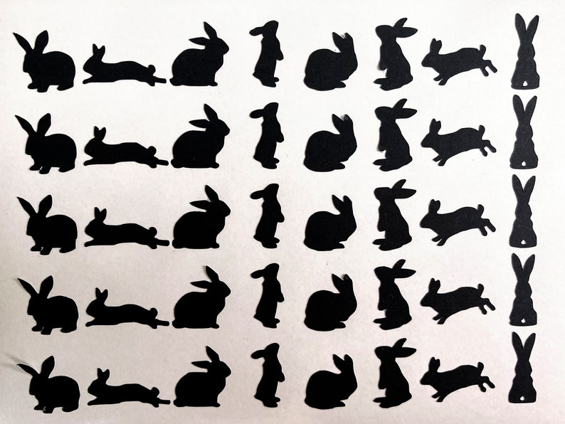 Puede incluir: Una hoja de papel negro con 20 siluetas de conejos recortadas. Los conejos est&aacute;n en varias poses, incluyendo de pie, sentados y saltando.