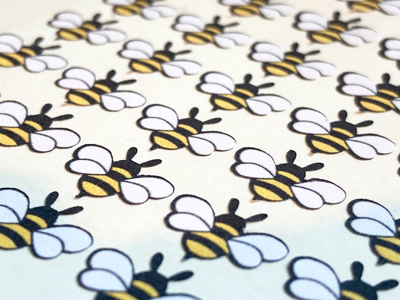 May include: A sheet of white paper with a repeating pattern of black and yellow bees with white wings. The bees are arranged in rows.