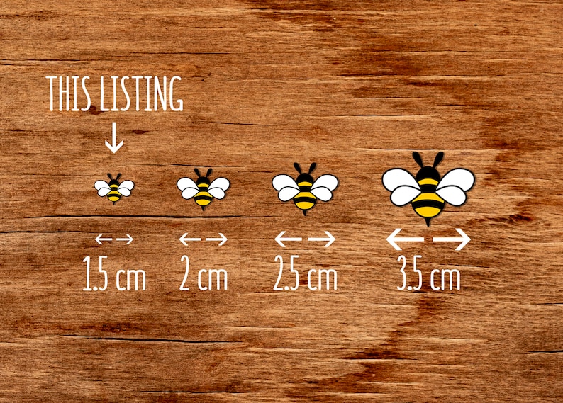 May include: Four bee illustrations on a wood background. The bees are black and yellow with white wings. The bees are shown in different sizes with measurements in centimeters: 1.5 cm, 2 cm, 2.5 cm, and 3.5 cm.