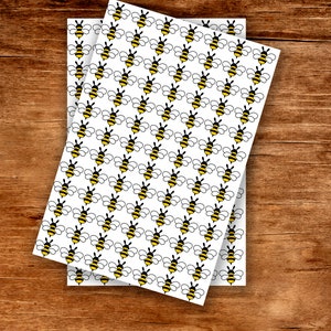May include: Two sheets of white paper with a repeating pattern of yellow and black cartoon bees.