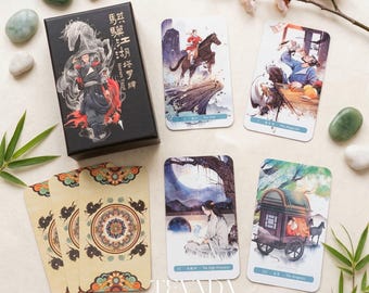 Puede incluir: Una baraja de cartas del tarot con una caja negra con una ilustración de un guerrero y un caballo. La baraja incluye varias cartas con ilustraciones de estilo acuarela que representan figuras y escenas. Piedras decorativas y flores rodean la baraja.
