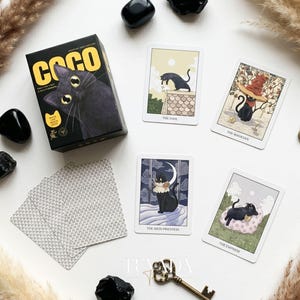 May include: A deck of Coco tarot cards featuring black cat illustrations. The box displays a black cat with large yellow eyes and the text COCO. Four cards are face-up showing The Fool, The Magician, The High Priestess, and The Empress.