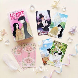 May include: A tarot card deck and several individual cards are displayed. The deck box is pink with the text "Heart Emotion Tarot" and an illustration of a couple. The cards feature romantic illustrations and floral designs.