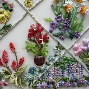 K&ouml;nnte beinhalten: Nahaufnahme einer floralen Bandstickerei. Das Kunstwerk zeigt verschiedene Blumen in Gelb-, Rot-, Lila- und Rosat&ouml;nen mit gr&uuml;nen Bl&auml;ttern. Die Blumen sind in einem Raster angeordnet, mit silbernen Akzenten.