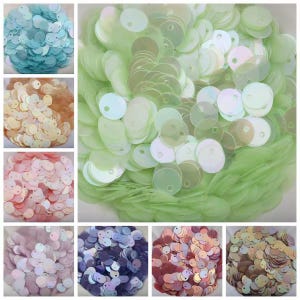 May include: A collection of circular sequins in various colors including light green, blue, peach, pink, lavender, dark purple, and metallic tones. Each individual sequin features a single hole near the edge and an iridescent finish.